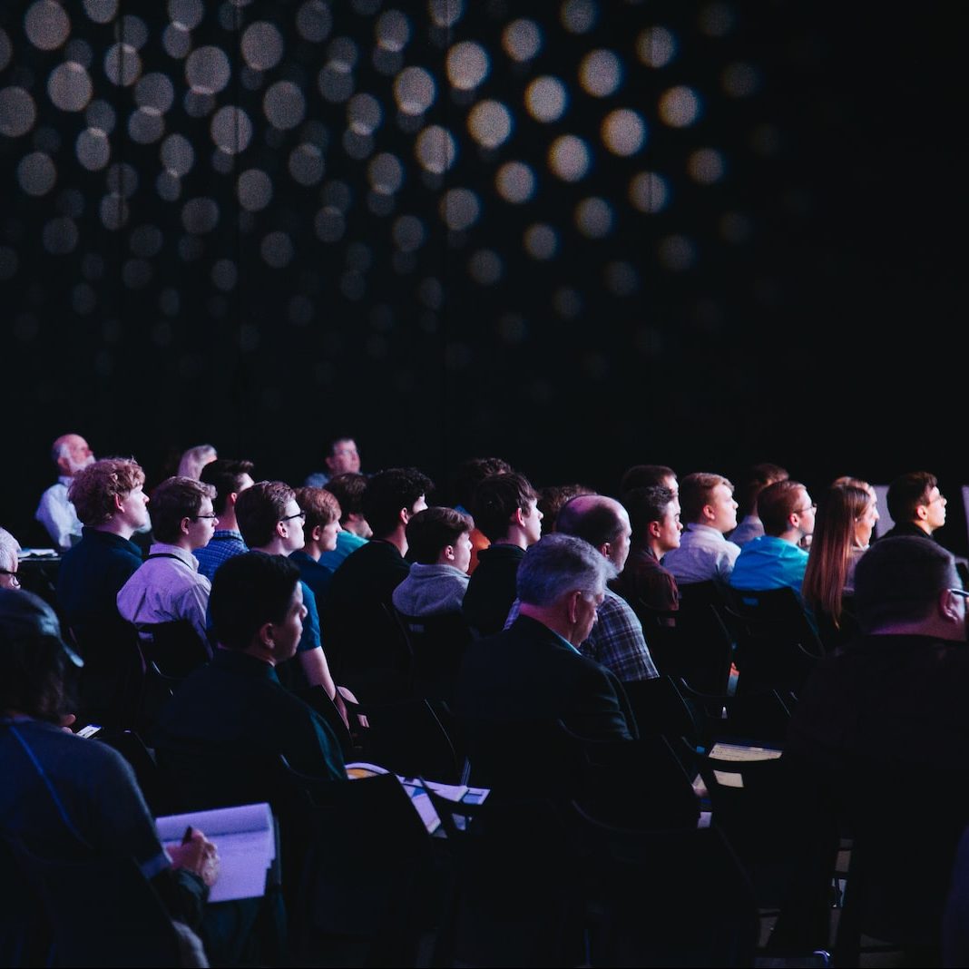 crowd of people sitting on chairs inside room